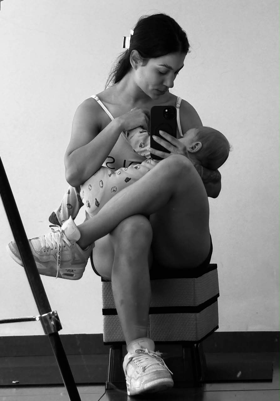 Foto da treinadora com bebê no colo, em momento de rotina real